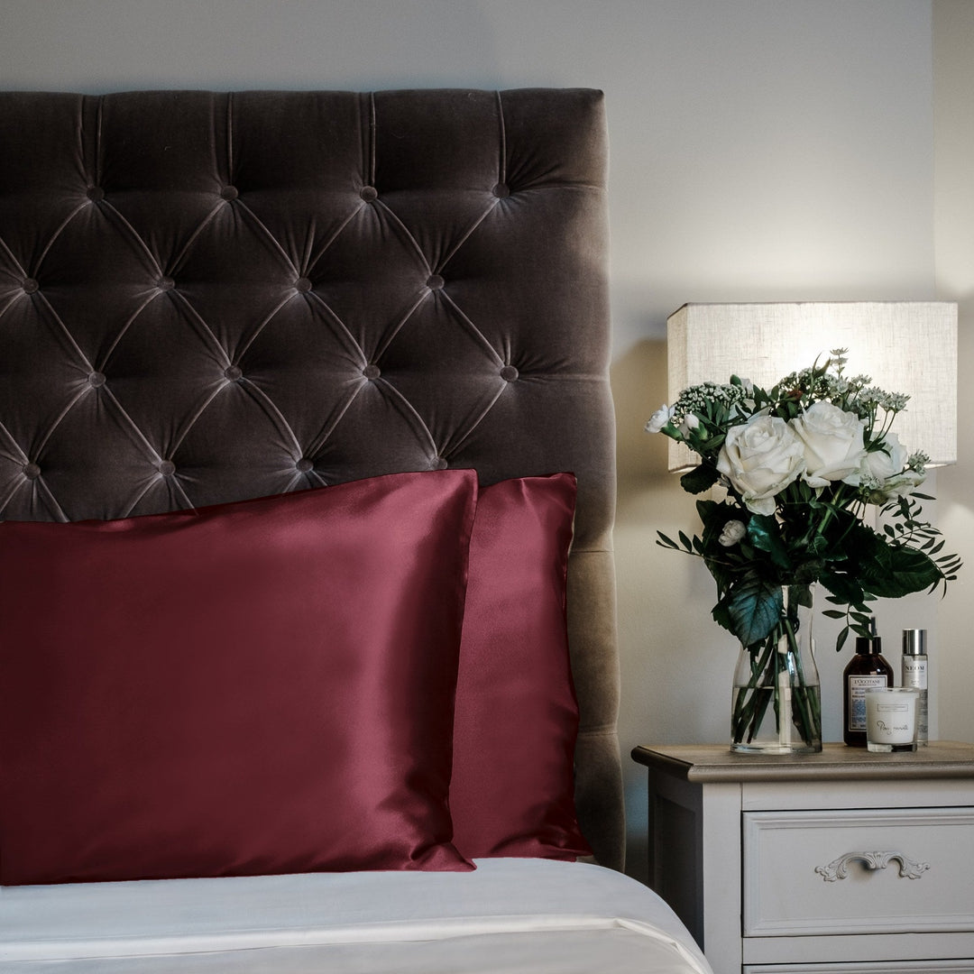 Maroon limited edition mulberry silk pillowcases on a velvet headboard