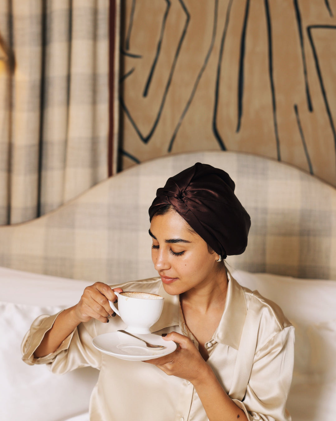 Espresso silk bonnet holding tea in bed close-up