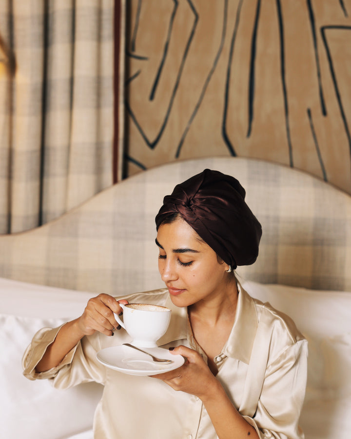 Espresso silk bonnet holding tea in bed close-up