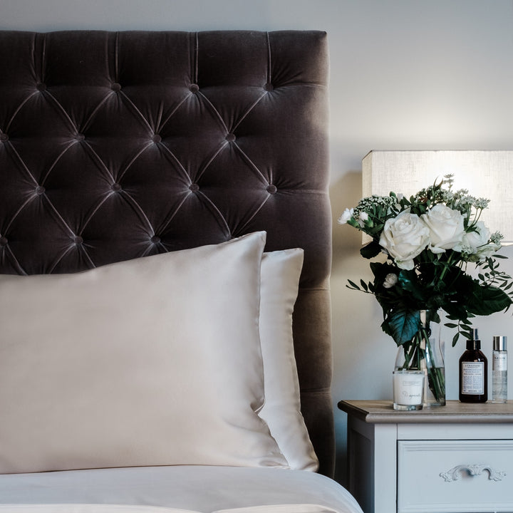 Champagne mulberry silk pillowcases for hair and skin, 22 momme 100% silk, on a velvet headboard | The Silk Collection