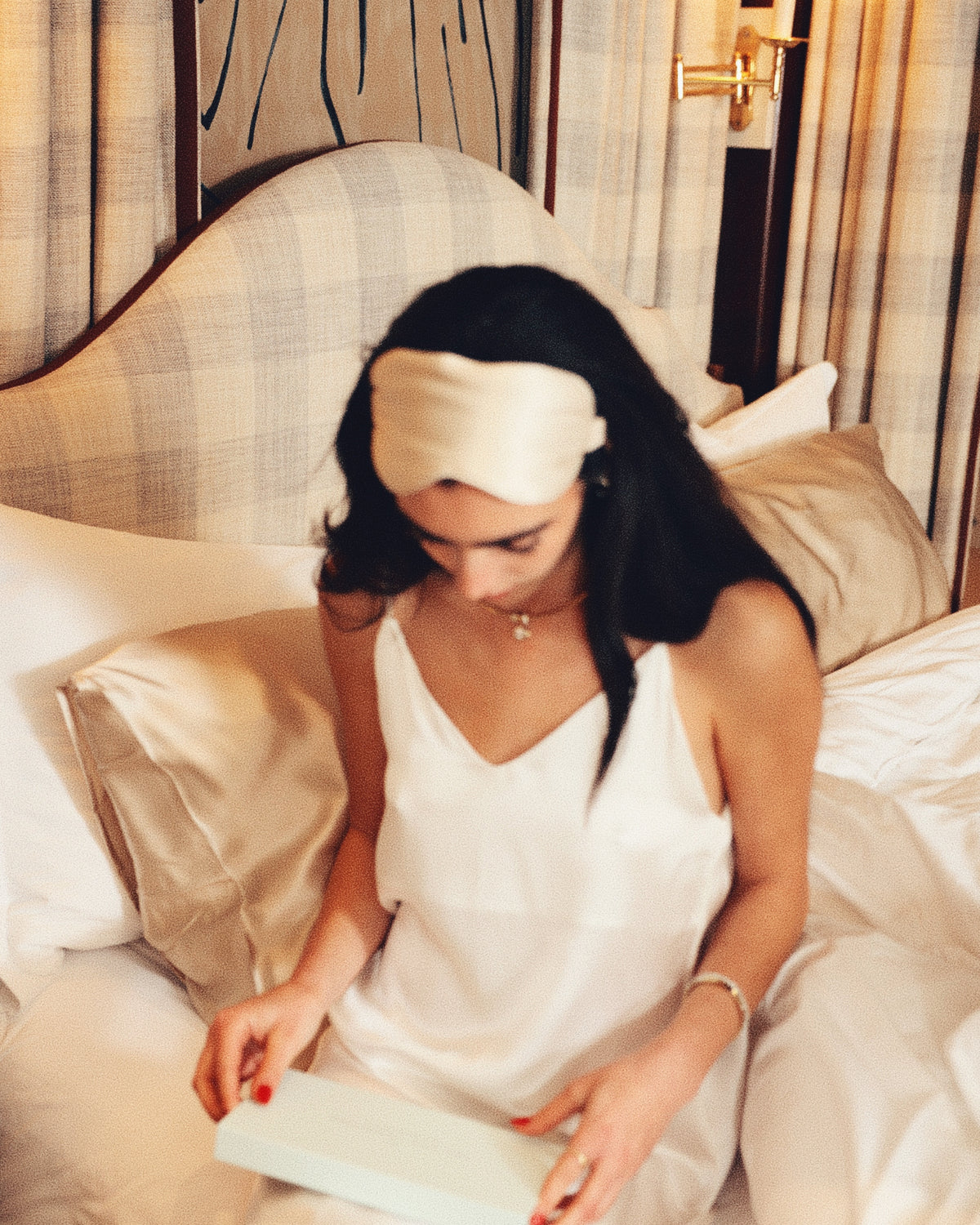 Pearl white silk slip champagne eye mask on head reading gift box in bed